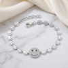 Silver bracelet with smiley face charms on a marble surface