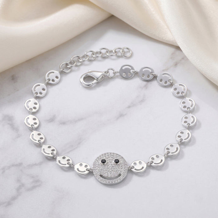 Silver bracelet with smiley face charms on a marble surface
