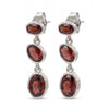 A pair of silver drop earrings featuring three faceted oval garnet stones in each earring, set in textured silver bezels on a plain white background.