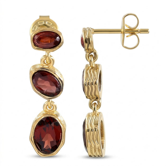 A pair of gold drop earrings with three oval garnet gemstones, shown on a plain white background with one earring facing forward and the other showing the post and backing.