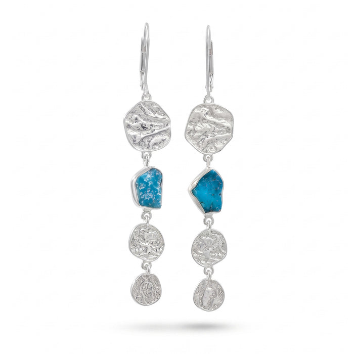 A pair of silver dangle earrings featuring textured silver discs, a small blue stone, and three smaller silver charms, shown on a white background.