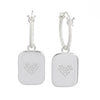 A pair of silver drop earrings featuring a textured rope chain and a square pendant engraved with a small heart design made of tiny clear stones, set against a plain white background.