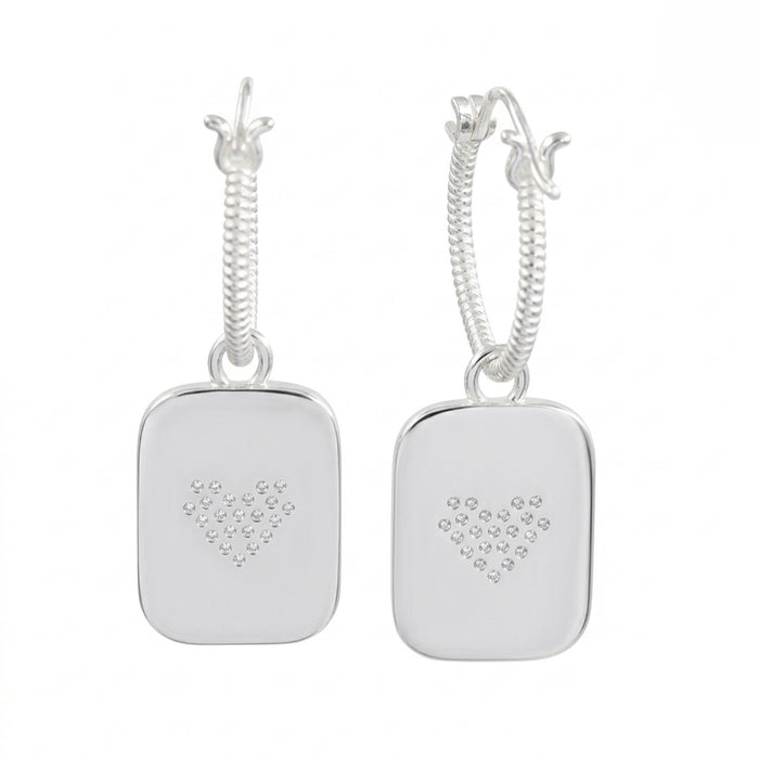 A pair of silver drop earrings featuring a textured rope chain and a square pendant engraved with a small heart design made of tiny clear stones, set against a plain white background.