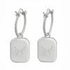 A pair of silver hoop earrings with rectangular drop pendants, featuring a small constellation design of dots on each pendant, set against a plain white background.