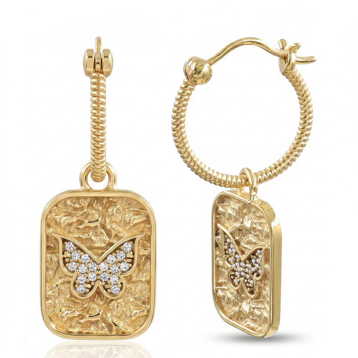 A pair of gold hoop earrings with textured rectangular dangles featuring a butterfly motif paved with small clear stones, shown on a white background.