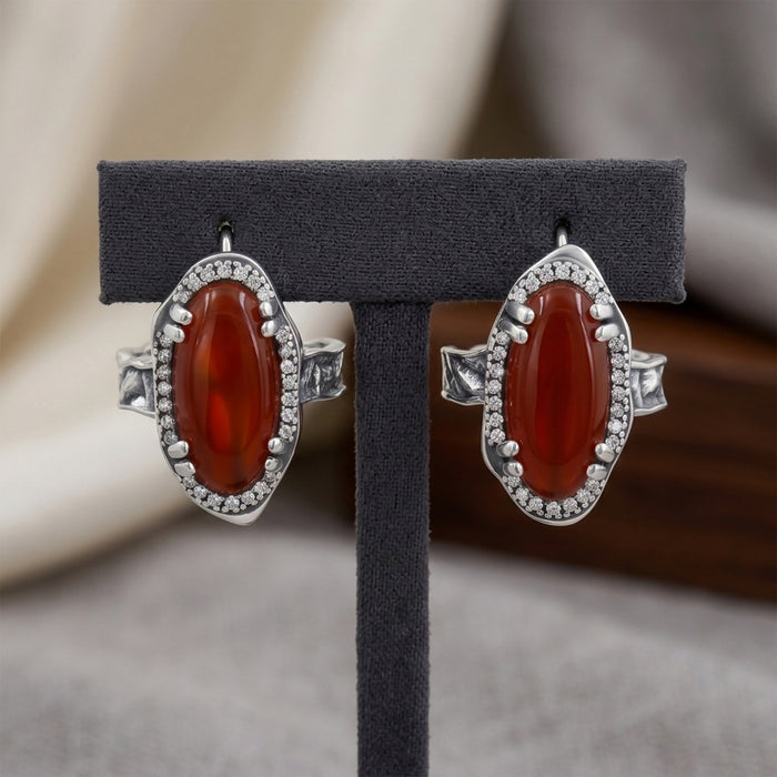Red onyx J-Hoop earrings with Swarovski crystals in silver plated finish, displayed on a black T-shape stand containing both earrings.