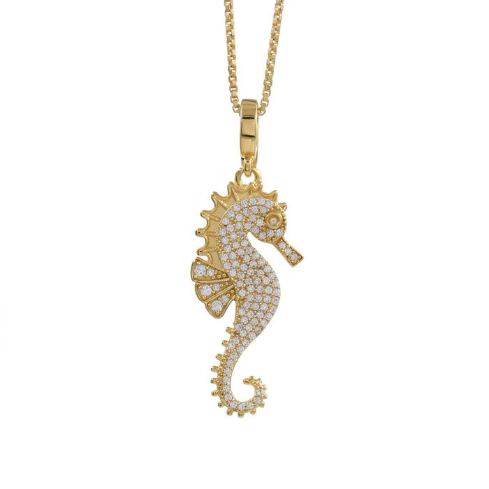 A gold seahorse pendant necklace paved with small clear stones, hanging from a gold chain against a plain white background.
