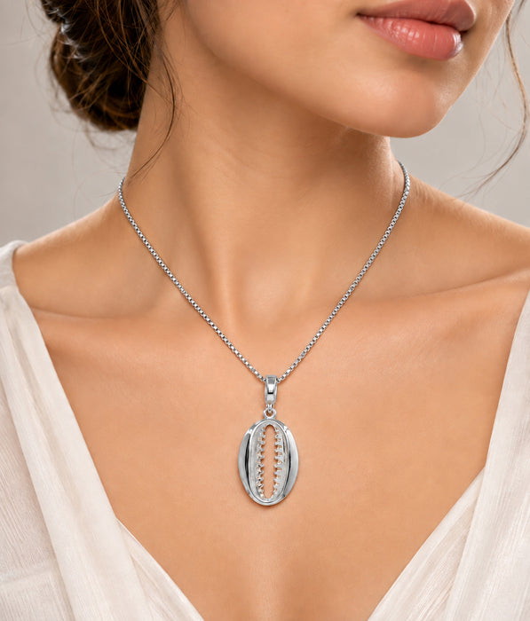 A close-up of a woman wearing a silver pendant necklace with a bohemian shell design featuring a central chain-link cutout.
