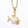 A gold fish pendant necklace featuring a large white pearl belly and a gold eye with tiny clear stones, suspended from a gold box chain on a white background.