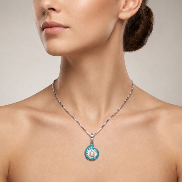 A close-up of a woman's neck and upper chest wearing a silver chain necklace with a round pendant featuring a white pearl or nautilus shell design.