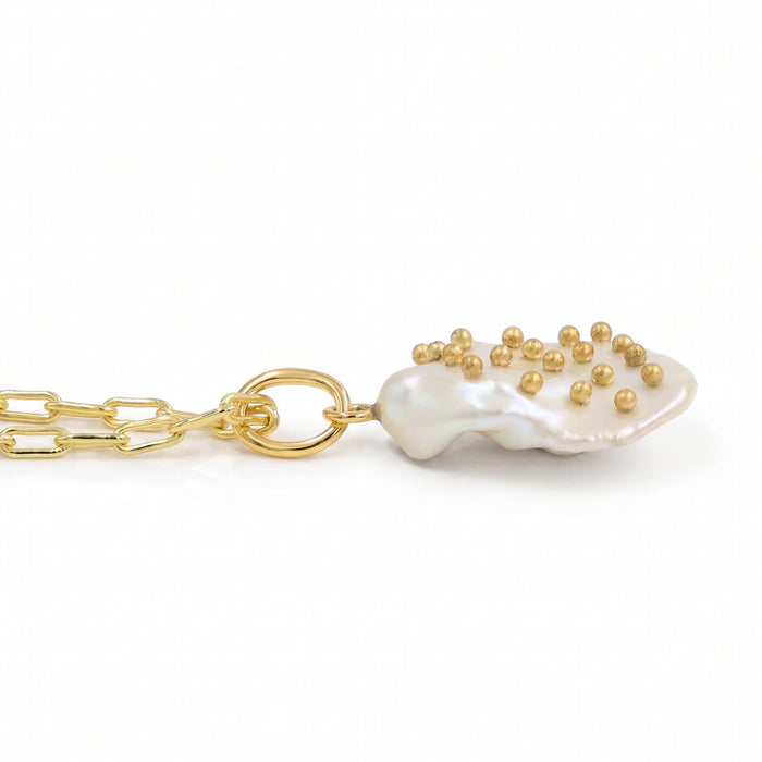 Side view of a gold paperclip chain necklace with a single free-size baroque freshwater pearl pendant featuring metal stud accents