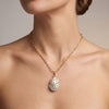 Model wearing a gold paperclip chain necklace with a baroque freshwater pearl pendant layered against a black top