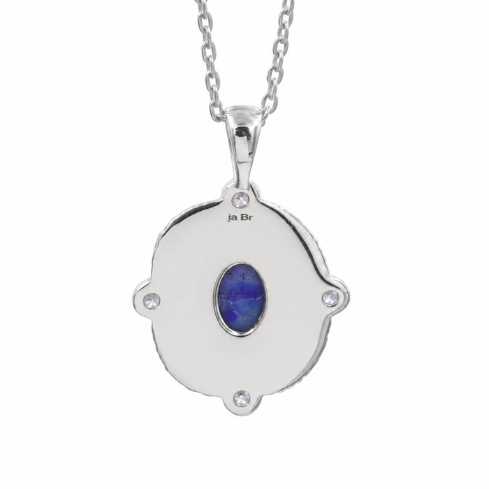 A silver pendant necklace featuring a scalloped circular design with a central oval blue lapis lazuli stone and small clear accent stones, shown on a white background.