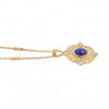 A gold pendant necklace featuring a central oval blue lapis lazuli stone surrounded by four clear round-cut gemstones, set in an ornate oval frame and suspended from a delicate gold chain.