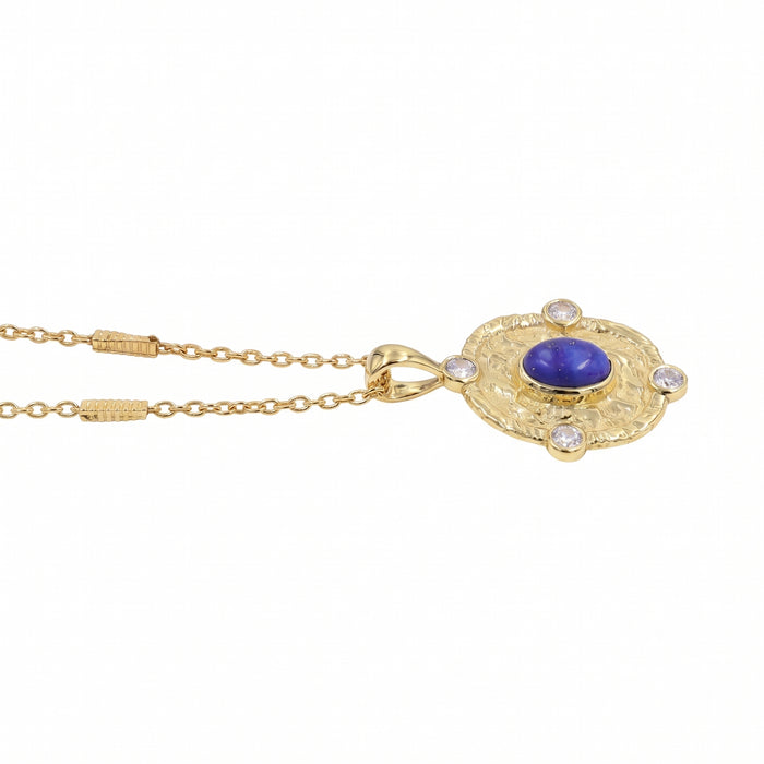 A gold pendant necklace featuring a central oval blue lapis lazuli stone surrounded by four clear round-cut gemstones, set in an ornate oval frame and suspended from a delicate gold chain.