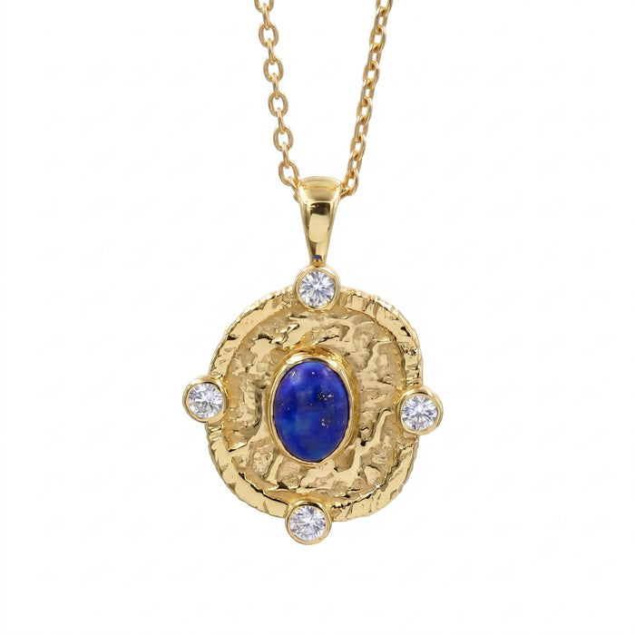 A gold pendant necklace featuring a textured circular medallion with a central deep blue lapis lazuli stone and four small clear round-cut accent stones, suspended from a gold chain against a plain white background.
