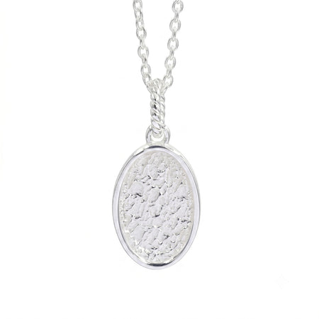 A silver oval pendant necklace with a textured, hammered finish inside a polished bezel setting, suspended from a delicate link chain against a plain white background.
