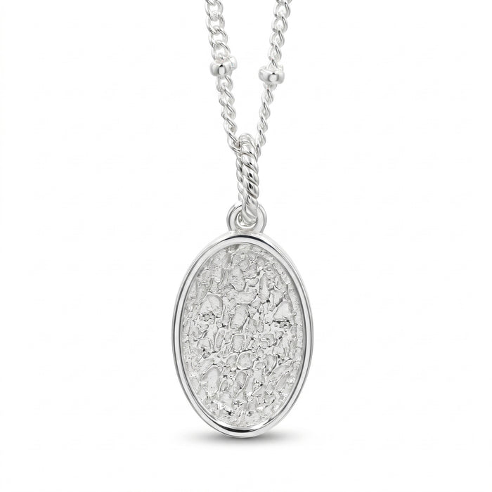 A silver oval pendant necklace featuring a textured, hammered or crackled metallic surface inside a polished bezel setting, suspended from a matching silver chain on a white background.