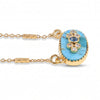 A gold chain necklace featuring an oval pendant with a light blue turquoise stone base and a central cluster of blue and clear gemstones, set against a plain white background.