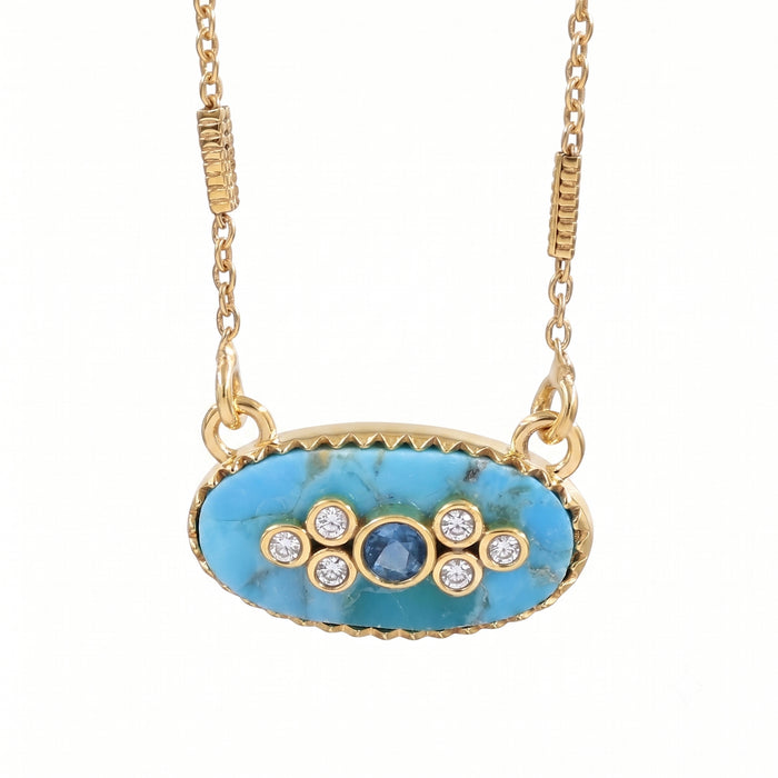 Gold oval pendant necklace featuring a turquoise-blue marbled stone center with a small round blue stone and five clear accent stones, suspended from a gold chain on a white background.
