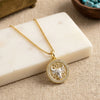Swarovski Crystal Taurus bull pendant necklace in 1 micron 18K gold plated finish, suspended from a gold box chain, displayed on a cream-colored marble block over a beige fabric background.