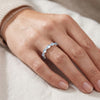 Close-up of a hand wearing a silver ring with Aquamarine blue gemstones on a neutral background