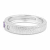 A textured silver band ring featuring a small purple oval gemstone on the left and a small round clear stone, shown on a plain white background.