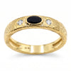 A textured yellow gold ring featuring a central oval black onyx and two round clear swarovski crystal on the shoulders, shown on a white background.