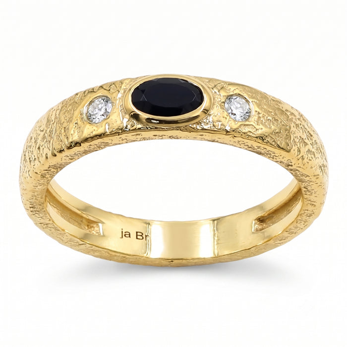 A textured yellow gold ring featuring a central oval black onyx and two round clear swarovski crystal on the shoulders, shown on a white background.
