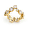 A gold ring featuring a series of hexagonal, round and square bezel-set clear gemstones, displayed on a clean white background.