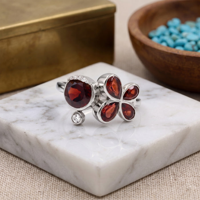 Natural garnet floral bypass ring with pear-cut garnet gemstones and Swarovski crystal accents in 18K gold & silver plated finish on a white background.