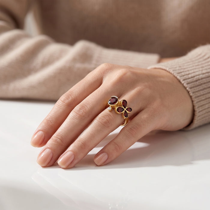 Natural garnet floral bypass ring with pear-cut garnet gemstones and Swarovski crystal accents in 18K gold & silver plated finish on a white background.