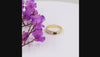 A textured yellow gold ring featuring a central oval black onyx and two round clear swarovski crystal on the shoulders, shown on a white background.