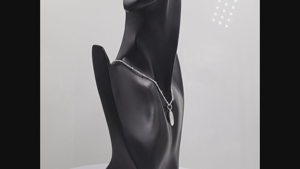 A silver oval pendant necklace featuring a textured, hammered or crackled metallic surface inside a polished bezel setting, suspended from a matching silver chain on a white background.