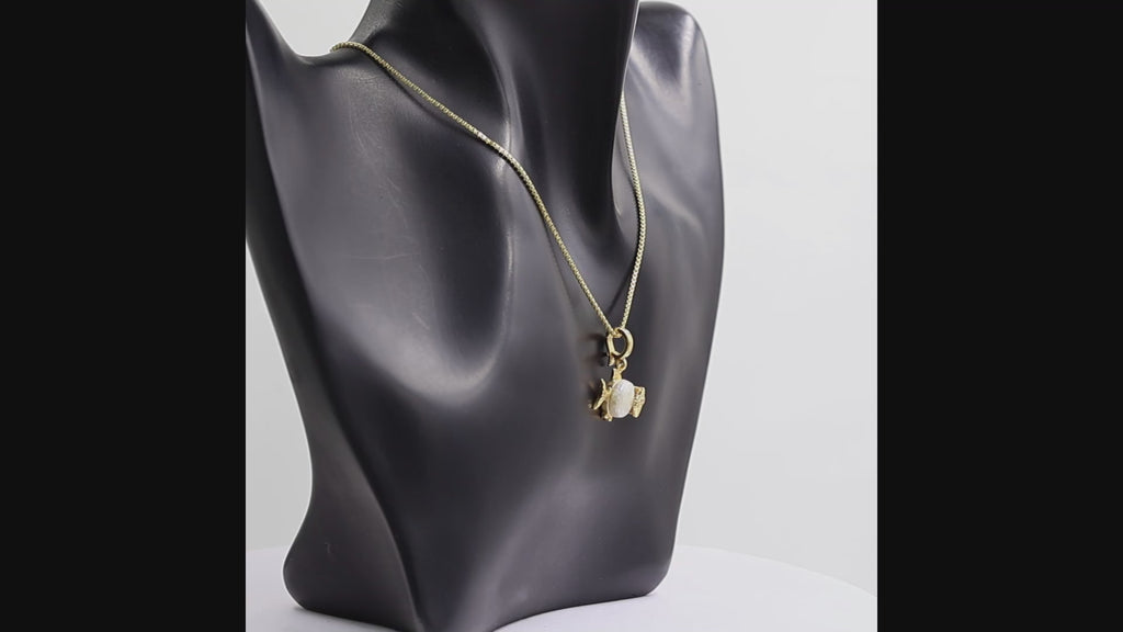 360 degree view of a gold fish pendant necklace featuring a large white pearl belly and a gold eye with tiny clear stones, suspended from a gold box chain on a white background.