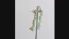 360 degree view of a pair of gold ear climber earrings featuring a vertical line of pear-shaped light aqua gemstones, shown  on a white background.